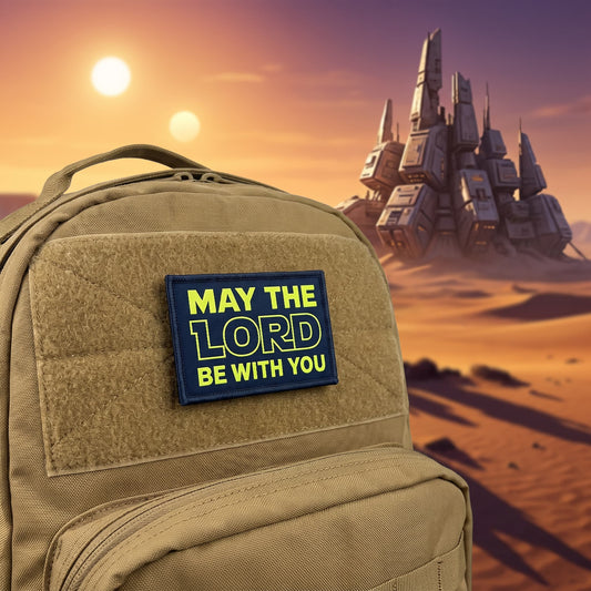 May The Lord Be With You morale patch with Yellow Star Wars styled lettering on a black background, 2x3 inch hook-and-loop fabric patch against a sci fi background
