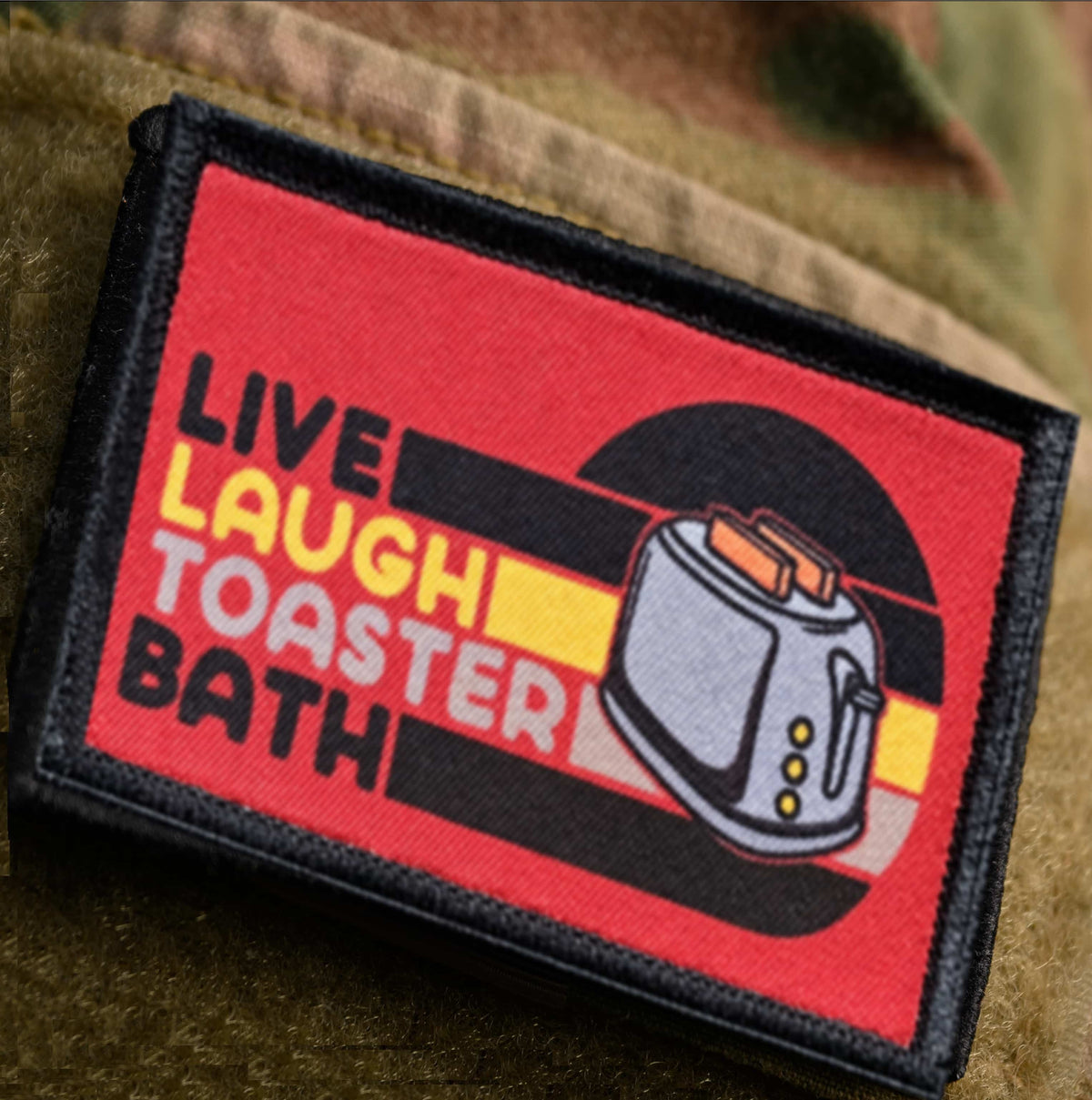 Live Laugh Toaster Bath morale patch attached to an OCP military jacket sleeve loop panel
